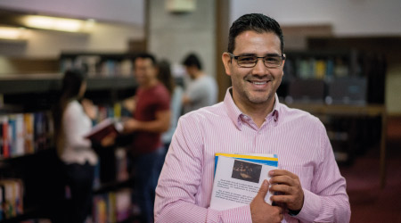 Foto de una persona en la biblioteca con un libro en sus manos