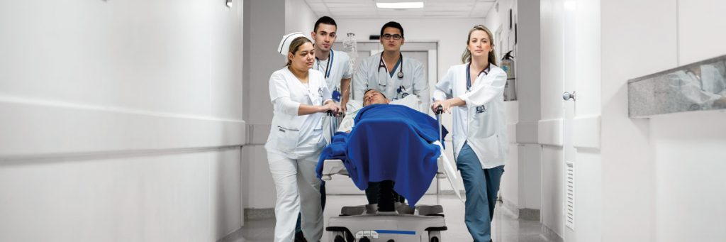 Foto estudiantes de medicina trasladando un paciente en una camilla.