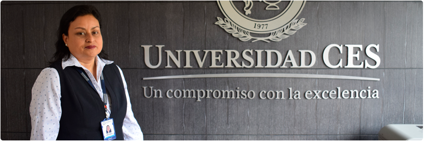 Foto de Witter Estrada junto al logo de la Universidad, en la oficina de rectoría